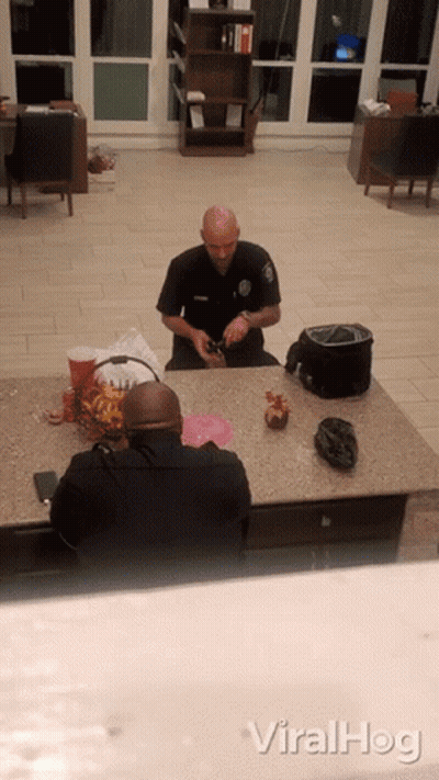 A Police Officer Sits At A Counter With Another Officer GIF