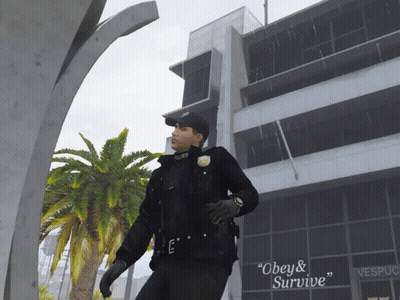A Police Officer Standing In Front Of A Building That Says Vespucci GIF
