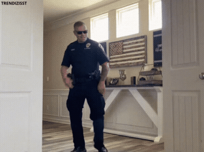 A Police Officer Standing In Front Of A Door With Trendizisst Written On It GIF