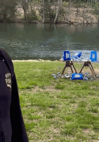 A Police Officer Stands In Front Of A Lake With A Few Coolers On The Ground GIF