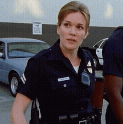A Police Officer Stands In Front Of A Sign That Says Parking GIF