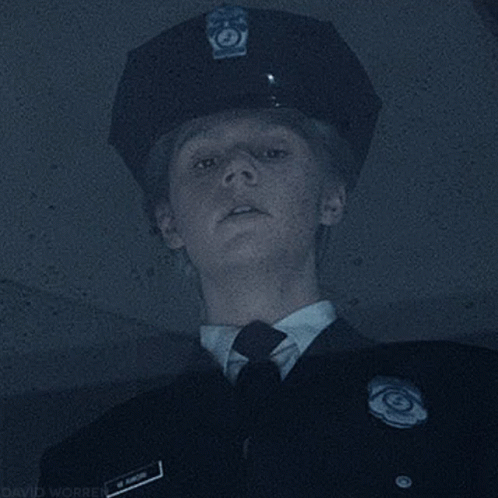 A Police Officer Wearing A Hat And Tie Is Looking Up At Something . GIF