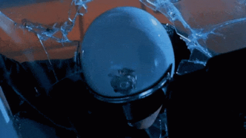 A Police Officer Wearing Sunglasses And A Helmet Stands In Front Of A Broken Glass GIF