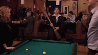 A Pool Table In A Bar With A Sign That Says Budweiser GIF