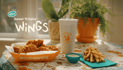 A Popeye 'S Advertisement Shows A Tray Of Chicken Wings And French Fries GIF