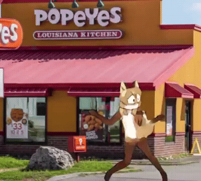 A Popeye 'S Louisiana Kitchen Restaurant With A Furry Character Standing In Front Of It GIF