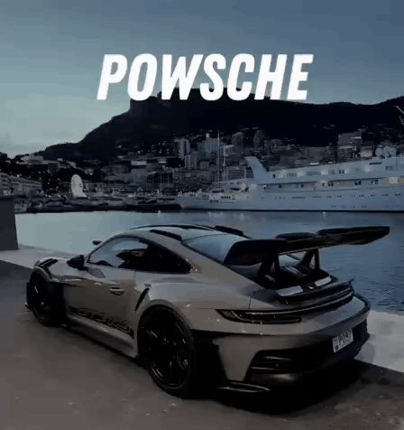 A Porsche Is Parked Next To A Body Of Water With A Boat In The Background . GIF