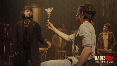 A Poster For Hadestown The Musical Shows A Man Holding A Woman 'S Hand GIF