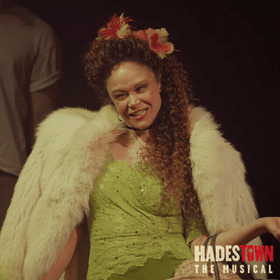 A Poster For Hadestown The Musical Shows A Woman In A Green Dress And Fur Coat GIF