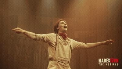 A Poster For Hadestown The Musical With A Man Holding A Red Flower GIF