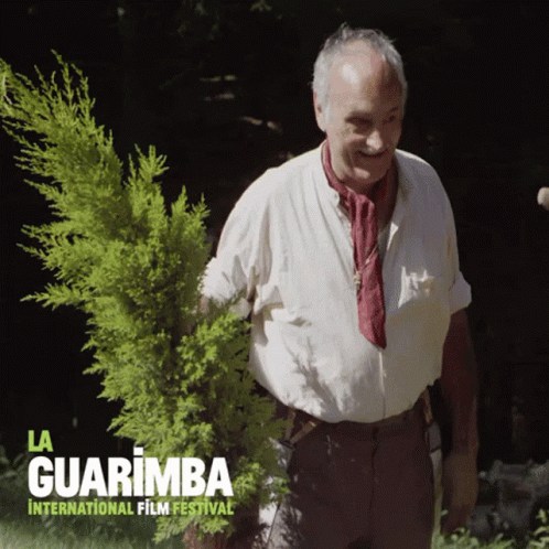 A Poster For La Guarimba International Film Festival Shows A Man Holding A Small Tree GIF