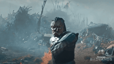 A Poster For Predator Badlands Shows A Man Standing In A Pile Of Trash GIF