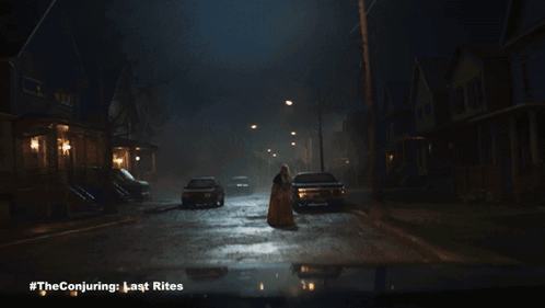 A Poster For The Conjuring Last Rites Shows A Woman Standing In The Middle Of A Street GIF