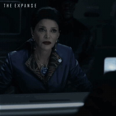 A Poster For The Expanse Shows A Woman Sitting At A Desk GIF