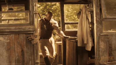 A Poster For The Jungle Cruise Shows A Man Holding A Rifle GIF