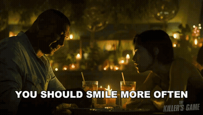 A Poster For The Killer 'S Game Shows A Man And A Woman At A Table GIF