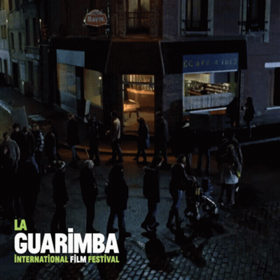 A Poster For The La Guarimba International Film Festival Shows A Group Of People Walking Down A Cobblestone Street GIF
