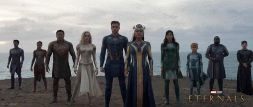 A Poster For The Movie Eternals Shows A Group Of Superheros Standing On A Beach GIF
