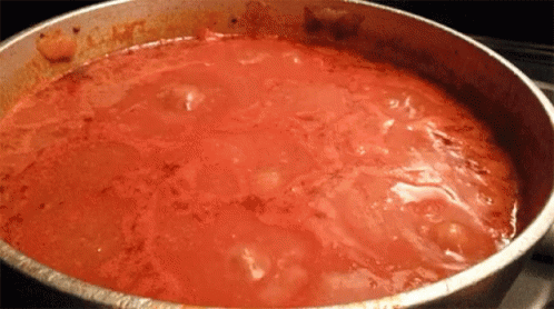 A Pot Of Tomato Sauce Is Being Cooked On The Stove GIF