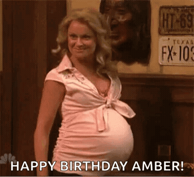 A Pregnant Woman With A Big Belly Is Standing In Front Of A Wall And Says `` Happy Birthday Amber '' . GIF