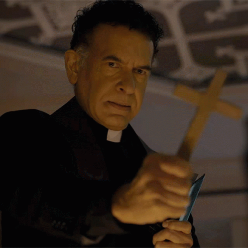 A Priest Is Holding A Knife In Front Of A Wooden Cross GIF