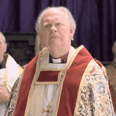 A Priest Wearing A Red And Gold Robe Stands In Front Of A Purple Background GIF