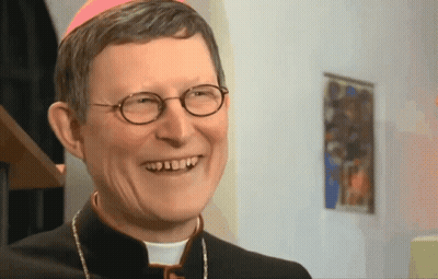 A Priest With Glasses And A Pink Hat Smiles GIF