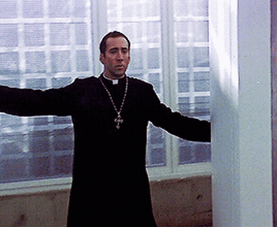 A Priest With His Arms Outstretched And A Cross On His Neck GIF