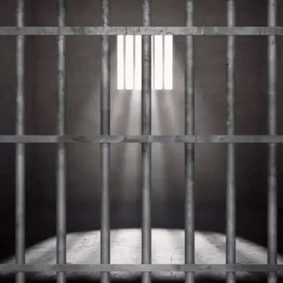 A Prison Cell With Bars And A Light Shining Through The Bars . GIF