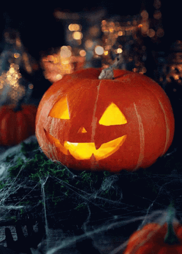A Pumpkin With A Face Carved Into It Is Lit Up In The Dark GIF
