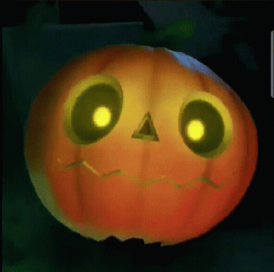 A Pumpkin With Glowing Eyes And A Face Carved Into It Is Sitting On A Table . GIF