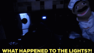 A Puppet In A Chef Costume Is Standing In A Dark Room With The Words What Happened To The Lights Written Below It GIF