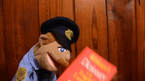 A Puppet In A Police Uniform Is Holding A Red Book With The Word Dictionary On It GIF