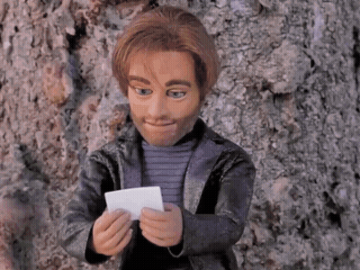 A Puppet Is Leaning Against A Tree And Holding A Piece Of Paper GIF