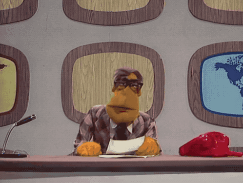 A Puppet Is Sitting At A Desk With A Microphone GIF