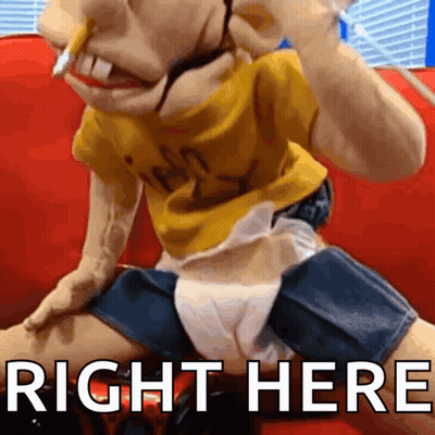 A Puppet Is Sitting On A Red Couch And The Words Right Here Are Above It GIF