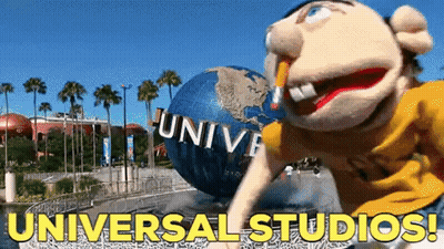 A Puppet Is Standing In Front Of A Giant Globe That Says Universal Studios On It GIF