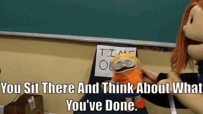 A Puppet Sits In Front Of A Sign That Says " Time Out " GIF