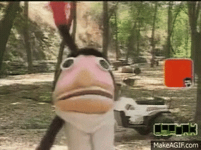 A Puppet With A Bird 'S Head Is Standing Next To A Golf Cart In A Forest . GIF
