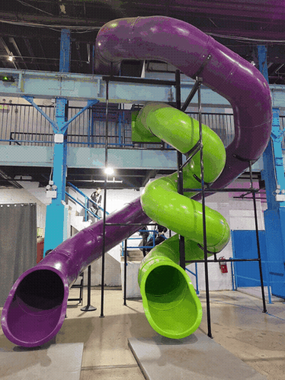 A Purple And Green Slide In A Building With Stairs GIF