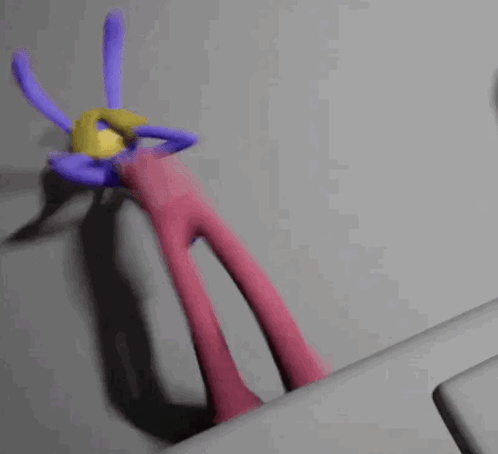 A Purple And Pink Cartoon Character With A Yellow Ball On Its Head GIF