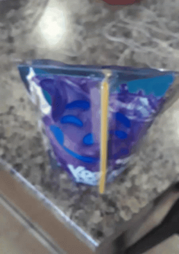 A Purple Bag With A Smiley Face On It Sits On A Table GIF