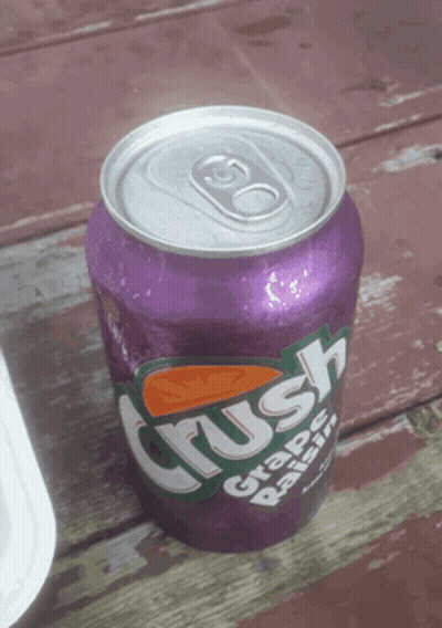 A Purple Can Of Crush Grape Raisin Soda On A Wooden Table GIF