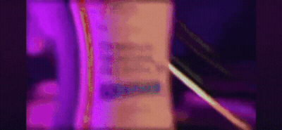 A Purple Light Is Shining On A Book With A Pen . GIF