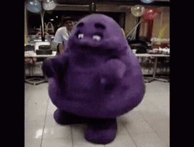 A Purple Mascot Is Dancing In A Restaurant With Balloons In The Background GIF