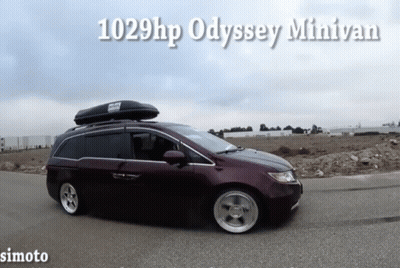 A Purple Minivan With A Roof Box On Top Is Driving Down A Road GIF