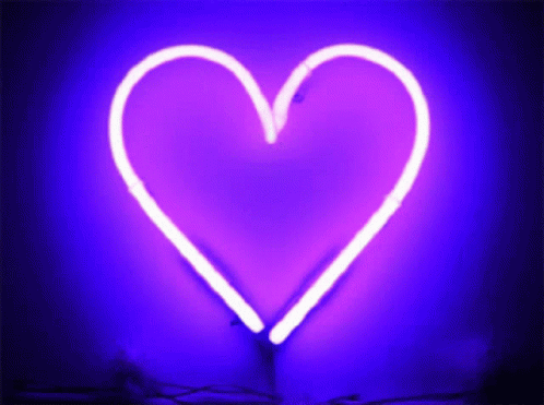 A Purple Neon Heart Is Lit Up On A Dark Purple Background GIF