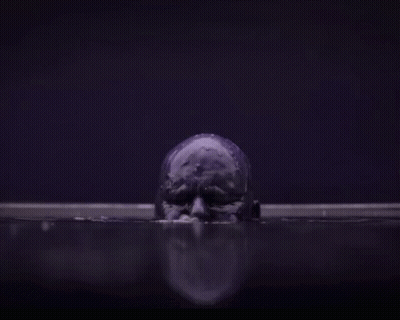 A Purple Skull Is Floating In A Dark Room In The Water . GIF