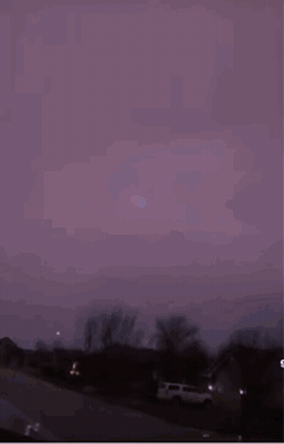 A Purple Sky With Lightning Strikes In The Distance GIF