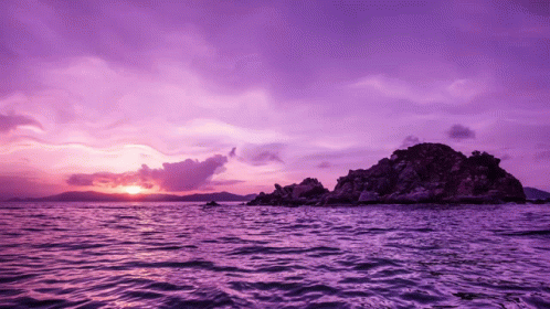 A Purple Sunset Over A Body Of Water With Mountains In The Background GIF